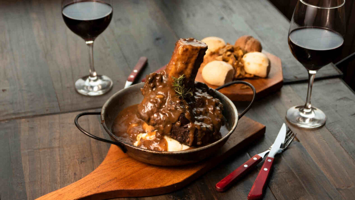 hearty family dinners depicted by this lamb shank with two glasses of red wine