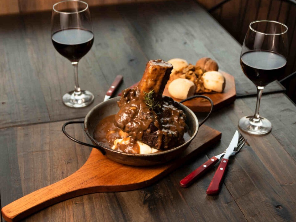 hearty family dinners depicted by this lamb shank with two glasses of red wine