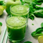 spinach and apple pieces around a green gut-friendly smoothie