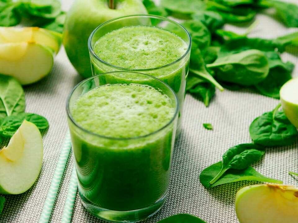 spinach and apple pieces around a green gut-friendly smoothie