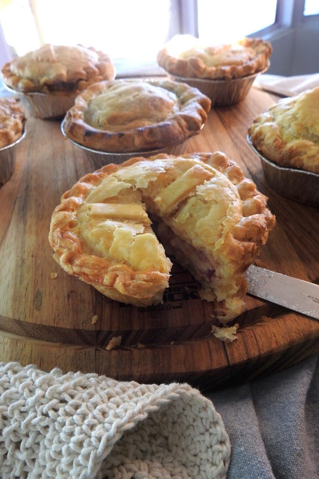 A darker gourmet-style pie with a deep brown crust and bold filling, styled in low moody lighting that emphasizes its rich flavour and indulgent character.