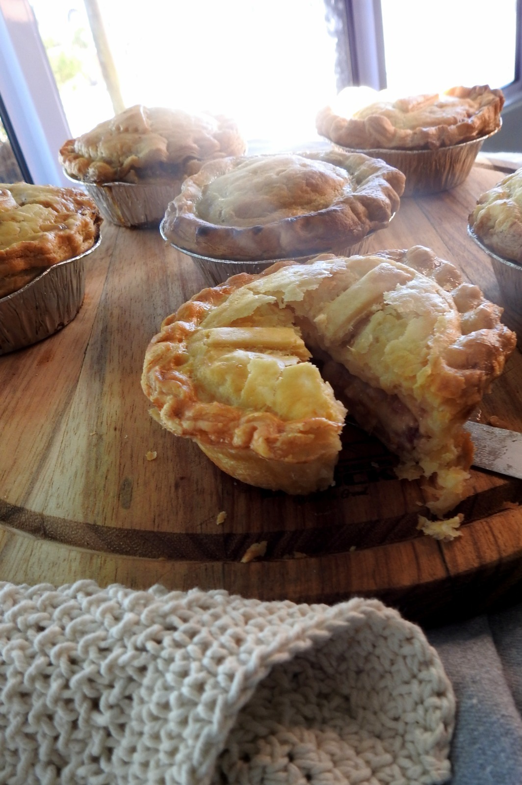 Savoury pies with a crisp golden crust and slow-cooked filling, presented in soft light that highlights its warm, comforting texture.