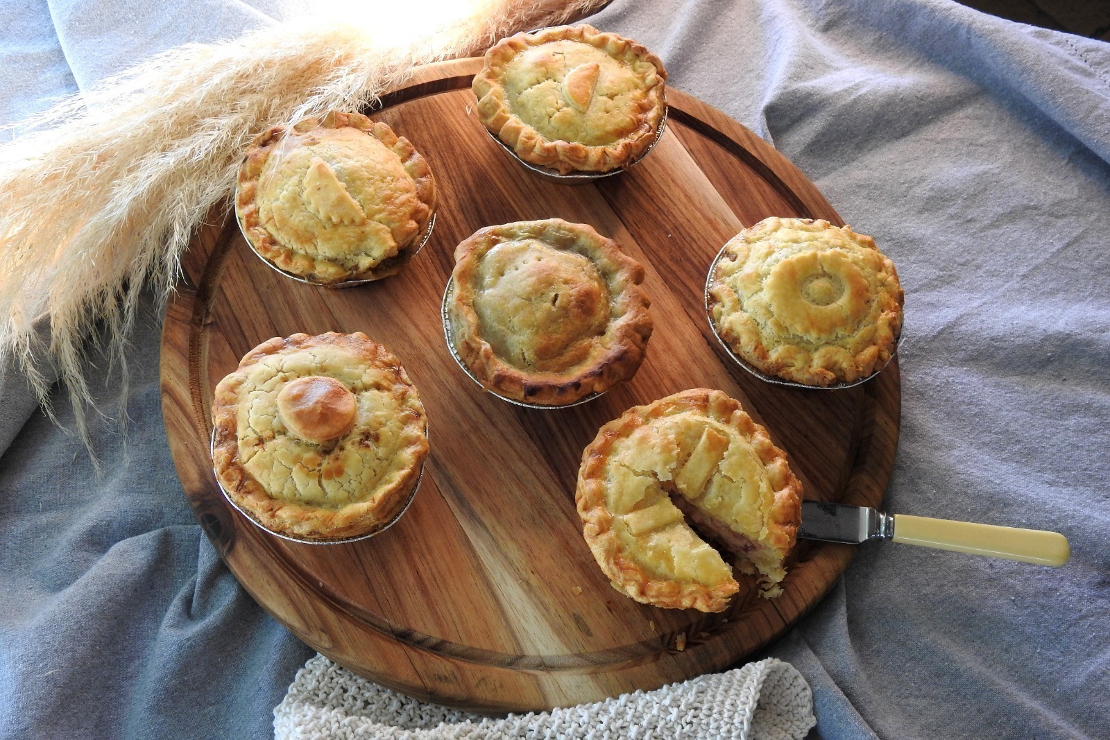 A Hearty pie with a golden, flaky pastry crust and rich slow-cooked filling, presented in soft ambient lighting that enhances its warm, comforting, homemade appeal