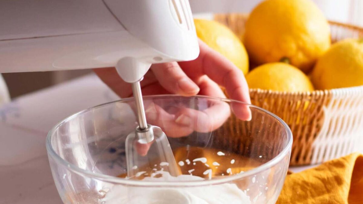 person using an electric whisk with a bowl of citrus fruit next to them, illustrating one of 5 smart baking hacks