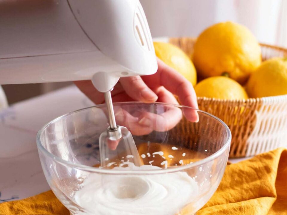 person using an electric whisk with a bowl of citrus fruit next to them, illustrating one of 5 smart baking hacks