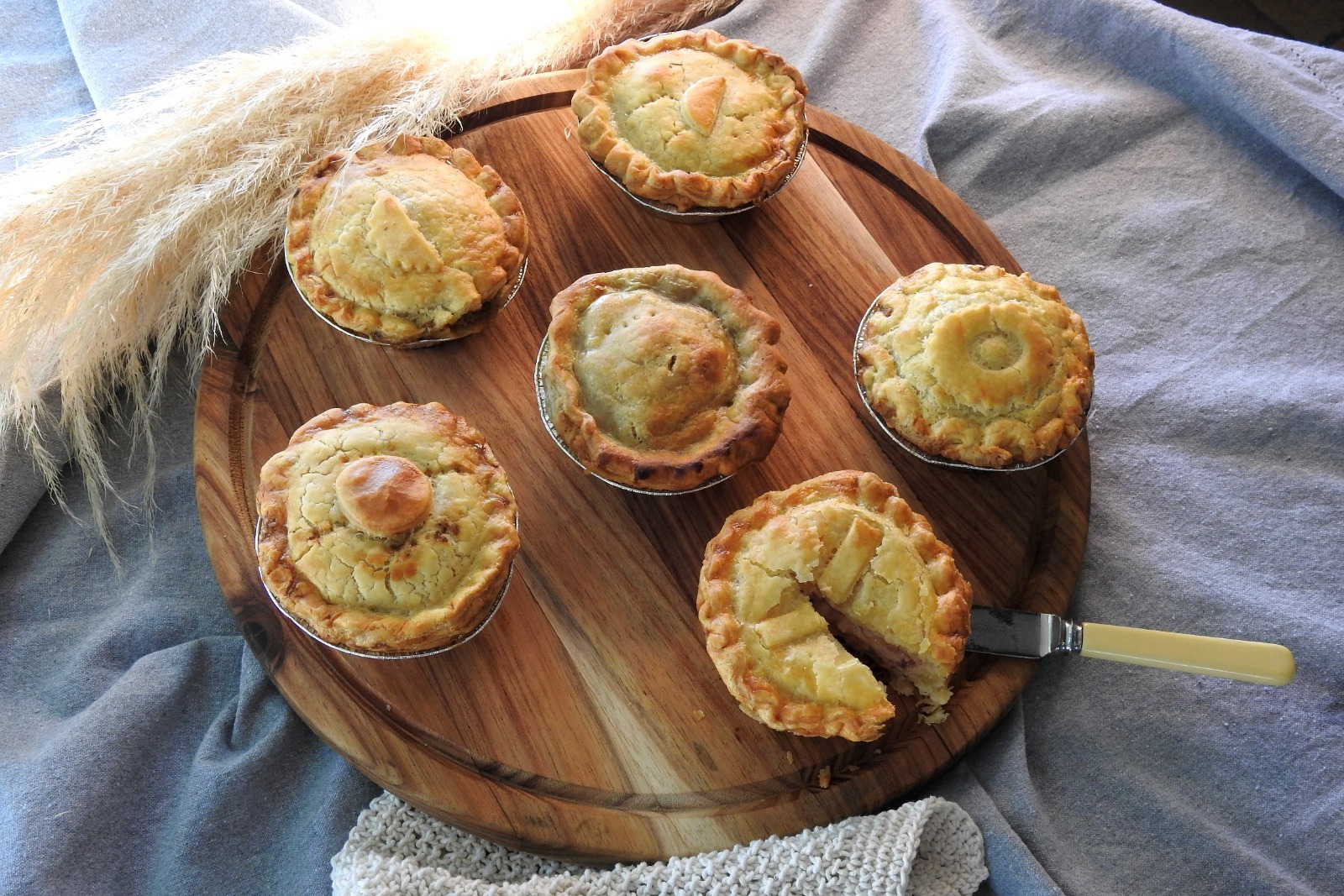 A Hearty pie with a golden, flaky pastry crust and rich slow-cooked filling, presented in soft ambient lighting that enhances its warm, comforting, homemade appeal