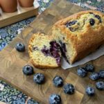 7 best easter recipes with a blueberry loaf on a bread board beside eggs and blueberries
