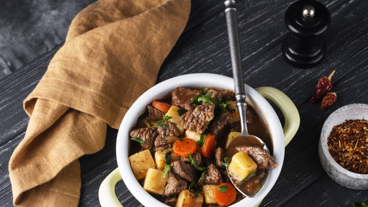 A rustic table set with classic homemade dishes including beef stew, bread pudding, and mashed potatoes, showcasing traditional old-school cooking.