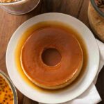 A selection of simple homemade desserts including rice pudding, chocolate pudding, bread pudding, and fruit jelly cups served in bowls on a rustic kitchen table.